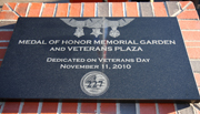 A new black granite marker is inscribed with an image of the medals and the plaza’s name.