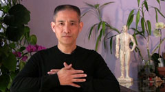 Nan Lu demonstrating a technique with hands placed upon his chest.